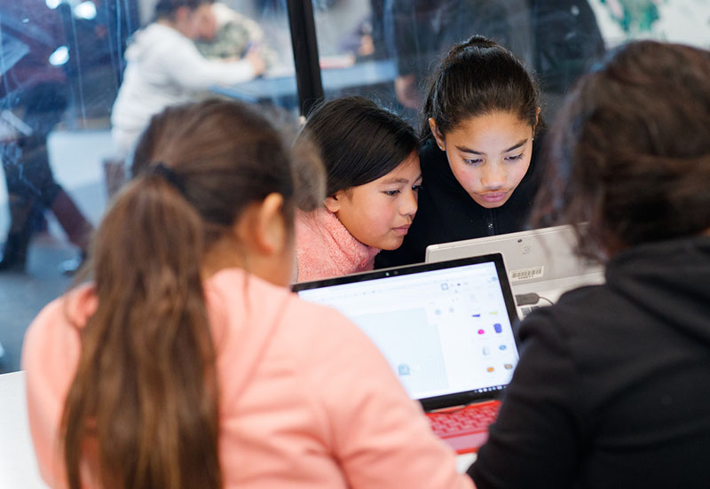 A group of young students work on a laptop