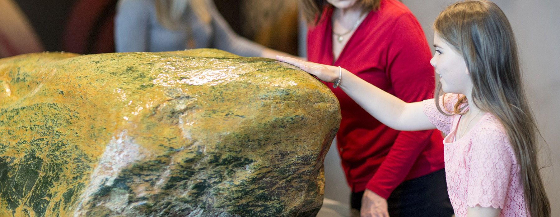 A little girl touches the greenstone in Te Marae