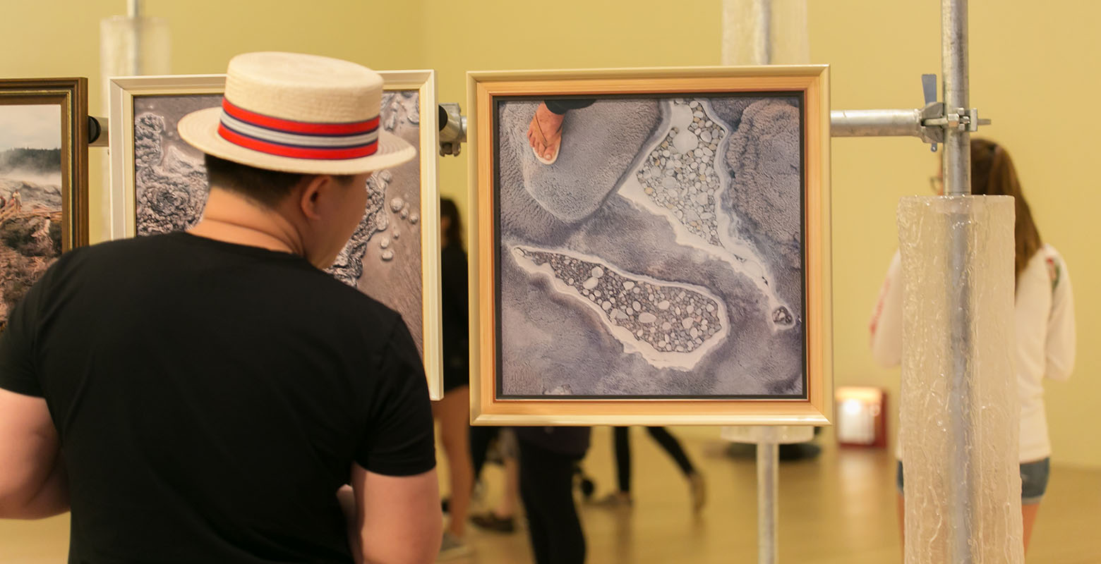 A man wearing a barbershop quartet-style hat looks at a photograph