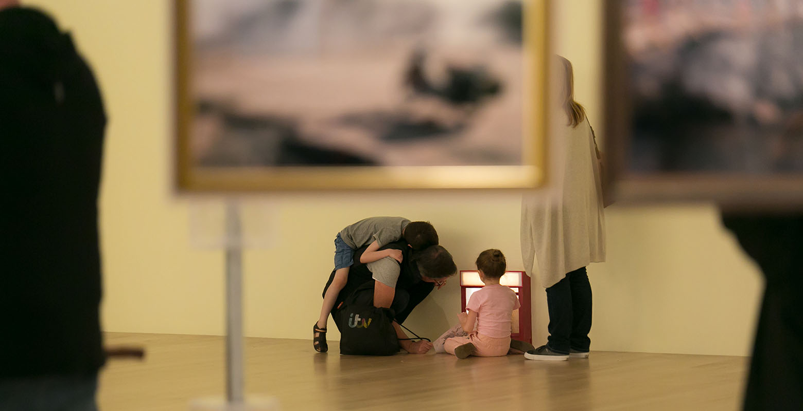 A group of people on the ground look at the artwork