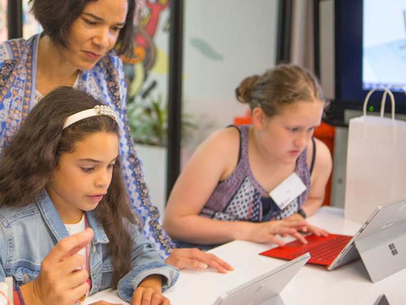 Adults and young girls in front of laptops