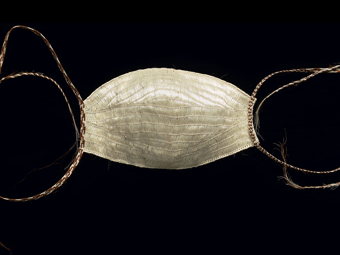 A face mask woven from flax muka on a black background