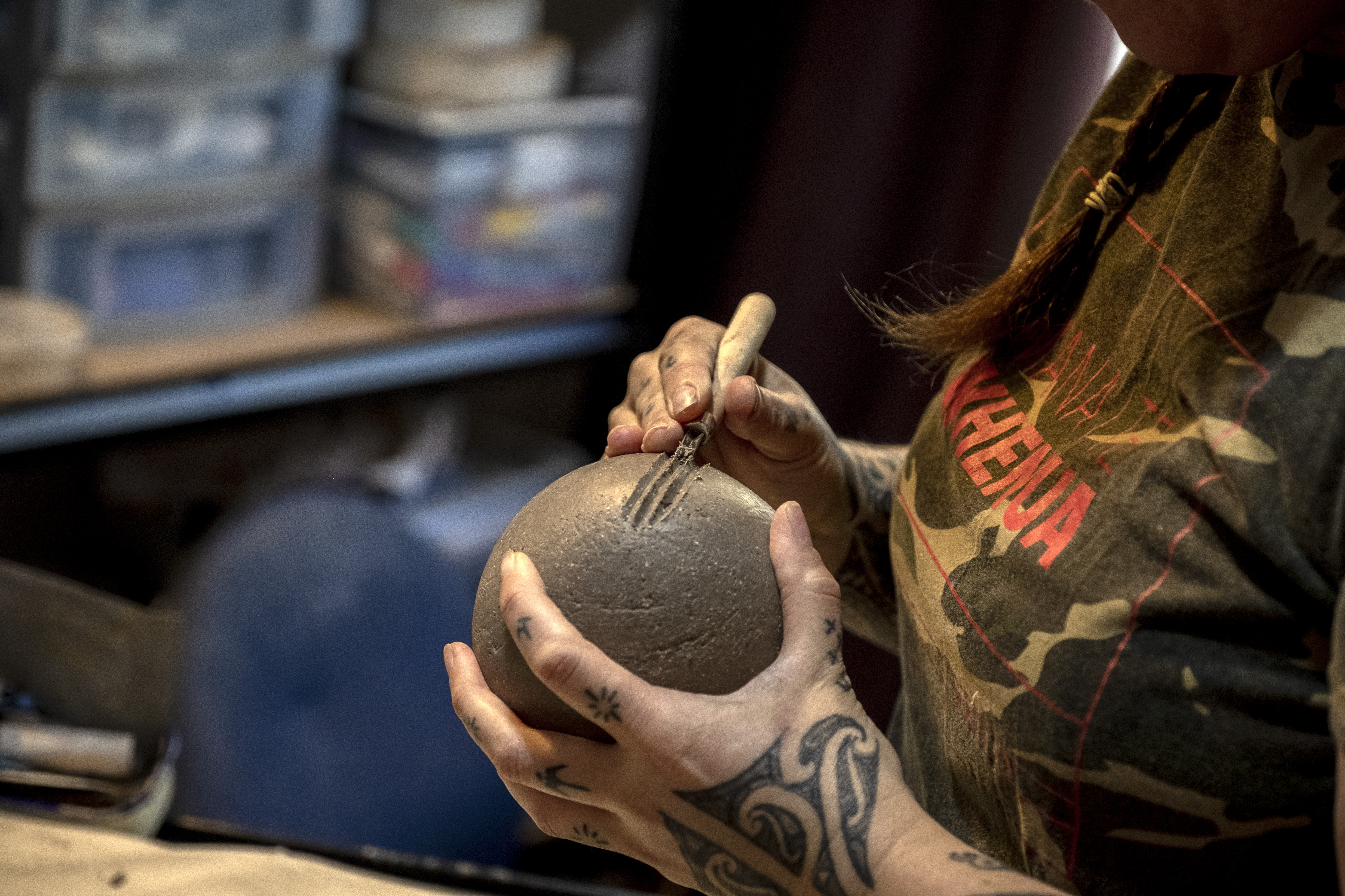 Two hands working on a piece of unfired clay pottery.