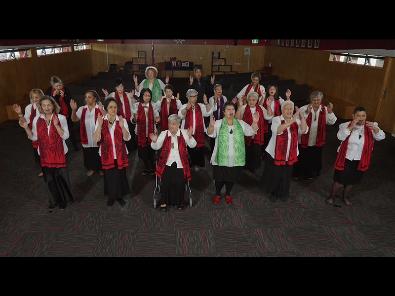 People in a large room performing a dance with actions