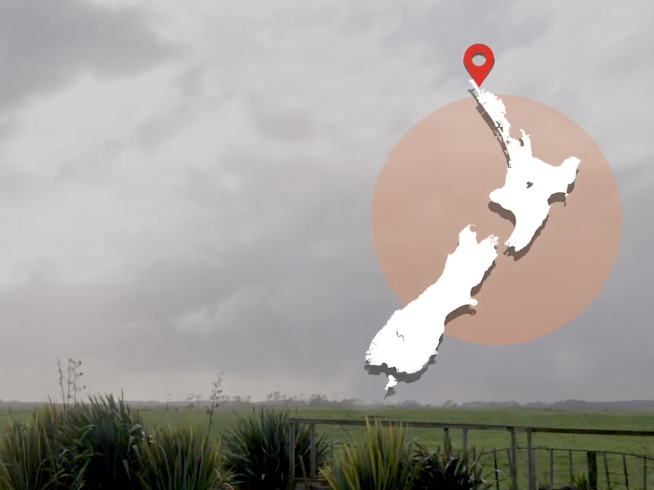 Grey sky over farmland. There's a map of New Zealand overlaid on the image on the top right-hand side.