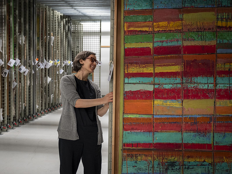 Lizzie pulls a rack out to look at a painting in the paintings storeroom