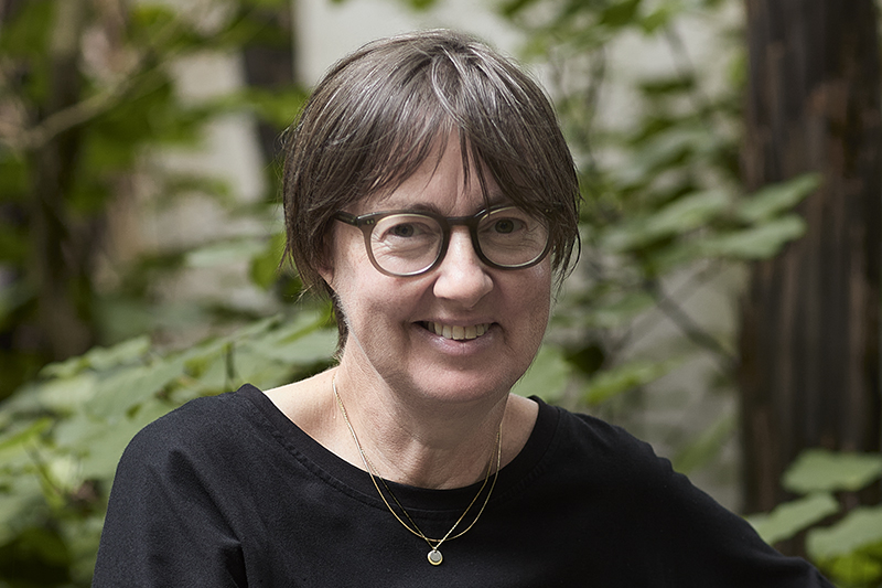 A head and shoulder image of a woman in glasses smiling at the camera.