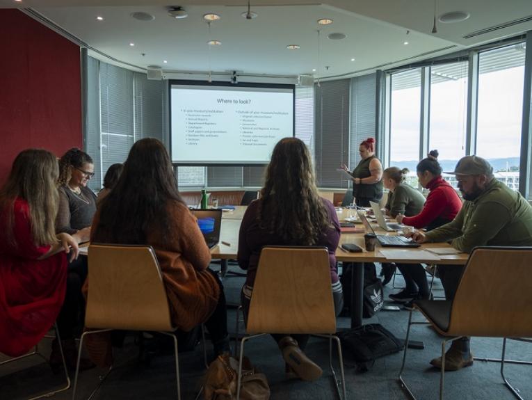 People gathered in a seminar room with someone talking at the front.