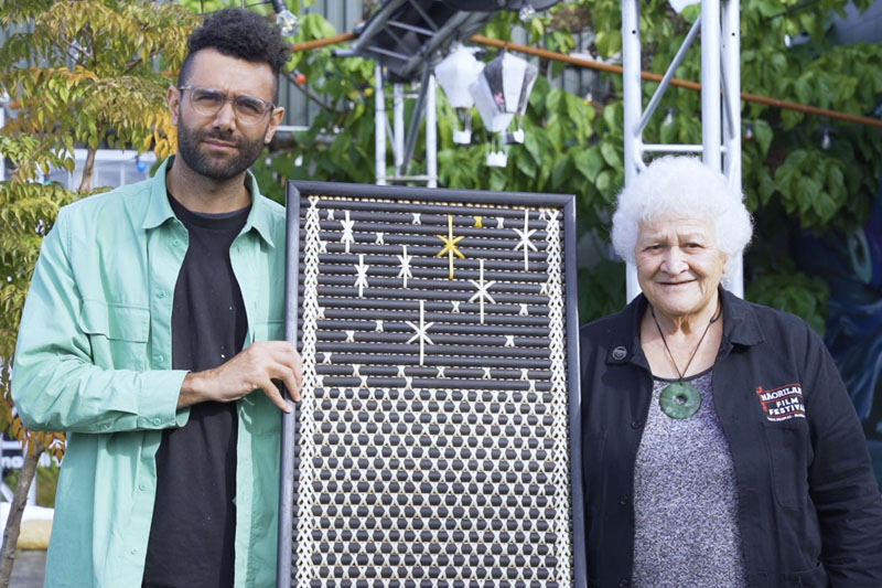 Tyrone Ohia and Sonia Snowden pose for the camera, with Tyrone holding Sonia’s tukutuku panel